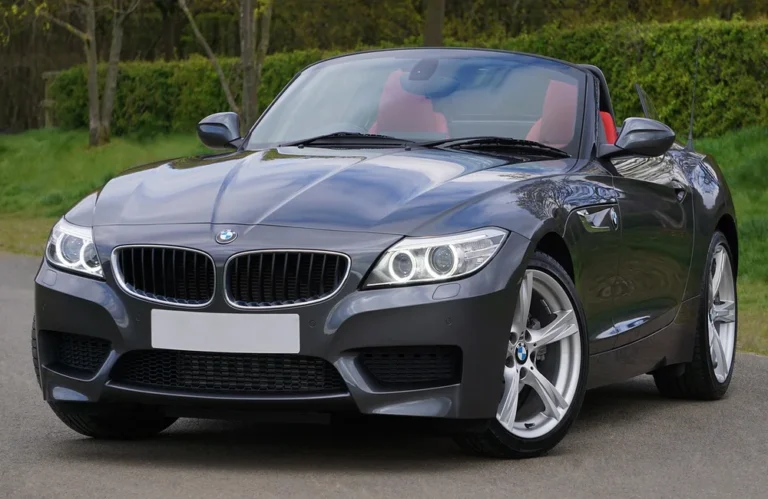 Voiture décapotable BMW grise avec intérieur rouge garée sur une route.