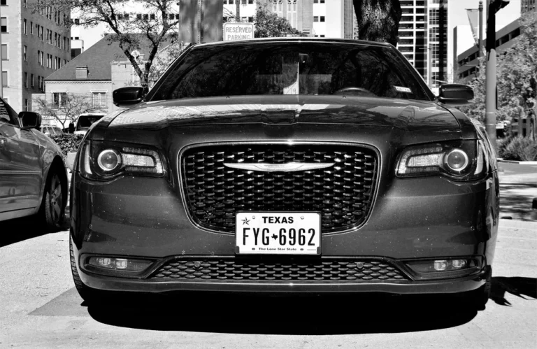 Voiture noire avec plaque texane, garée en milieu urbain.