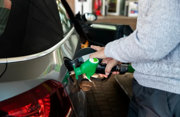 Personne faisant le plein d'une voiture avec une pompe à essence verte.