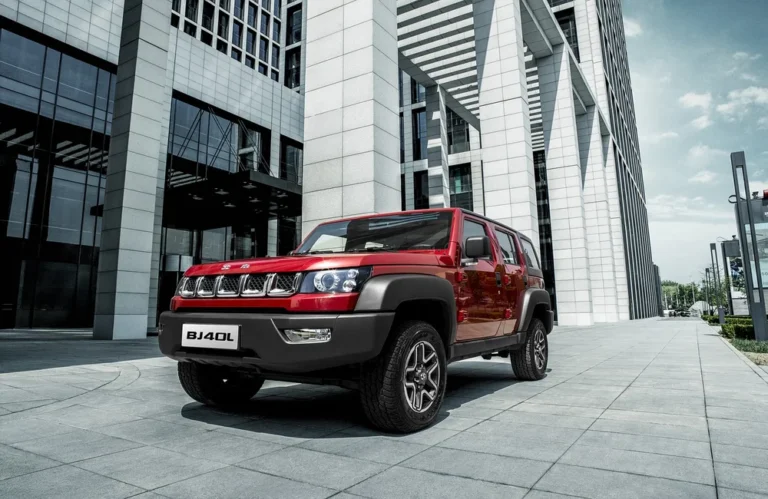SUV rouge stationné devant un bâtiment moderne en verre et acier.