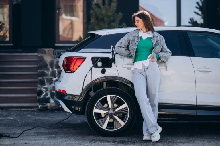 Femme appuyée sur une voiture électrique en charge.