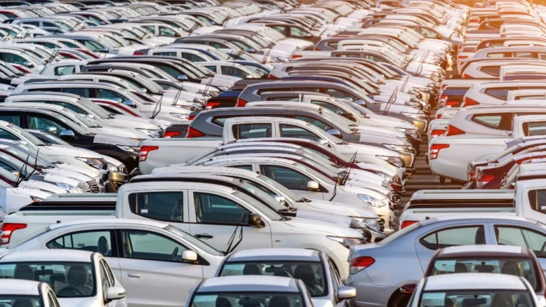 Rangée de voitures blanches stationnées dans un parking en plein air.