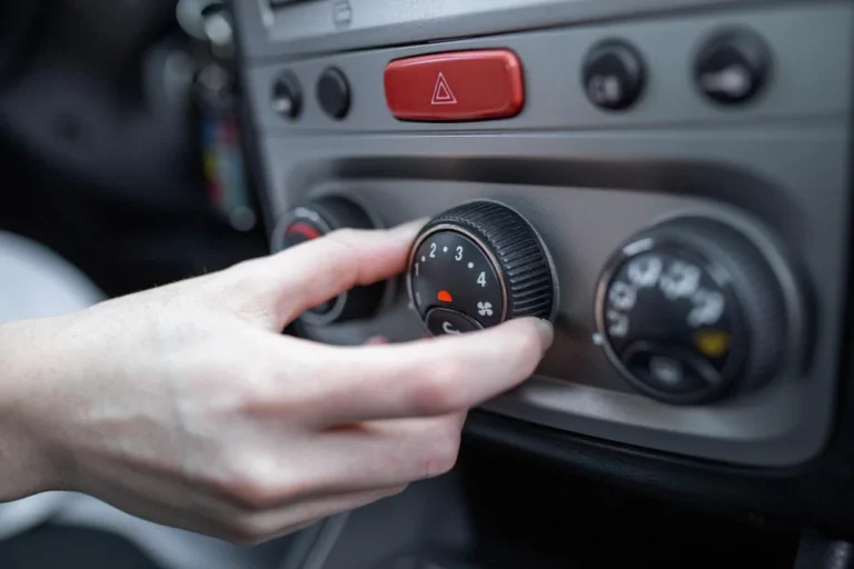 Main réglant le bouton de climatisation d'une voiture.