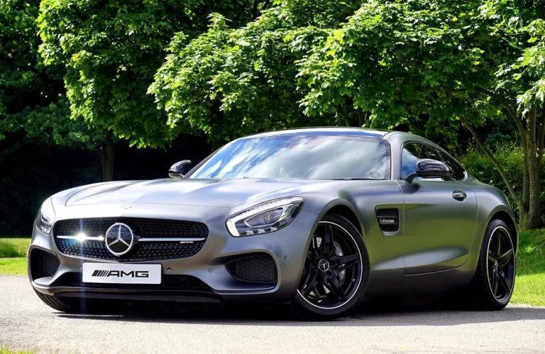 Voiture de sport Mercedes grise stationnée devant des arbres verts.
