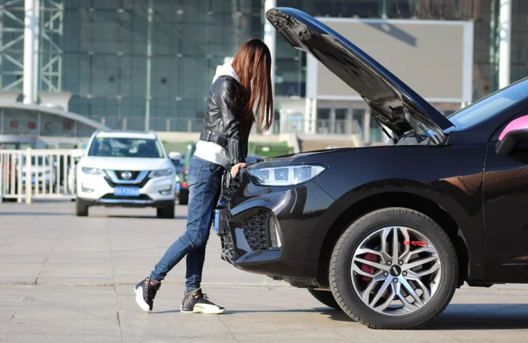 Femme vérifiant le moteur d'un SUV noir avec capot ouvert.