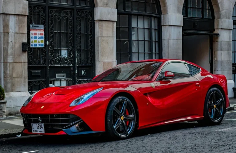 Voiture de sport rouge garée devant un bâtiment historique en pierre.