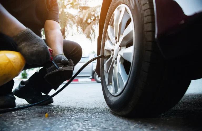 Personne vérifiant la pression d'un pneu de voiture avec un manomètre.