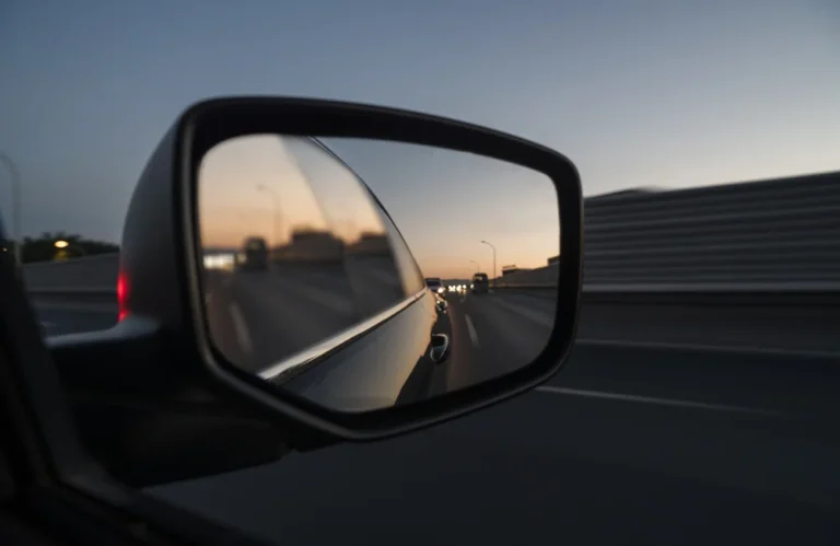Vue de la route au crépuscule dans un rétroviseur latéral.